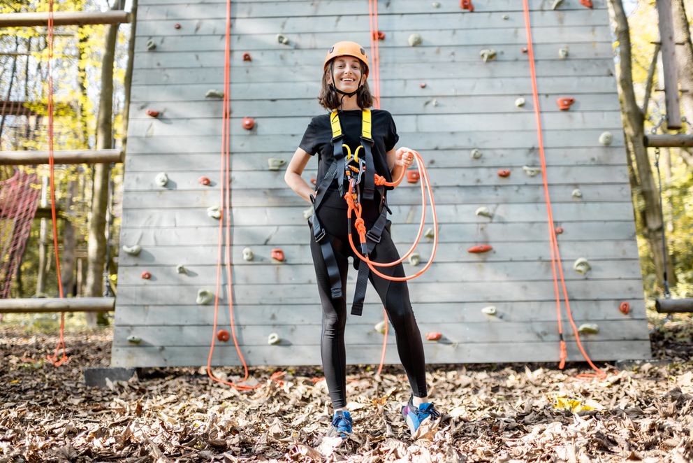 Gut ausgestattete Frau in der Nähe der Kletterwand